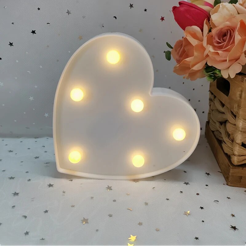 One white nightlamp heart illuminated by yellow LED's on a white tablecloth with silver and red heart glitter