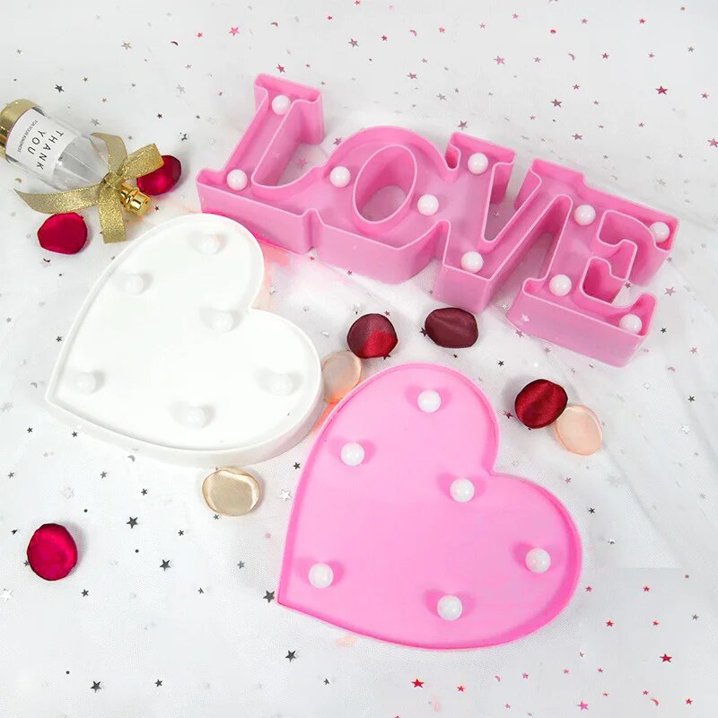 One pink nightlamp that reads LOVE and a pink and red heart lamp nonilluminated on a white background