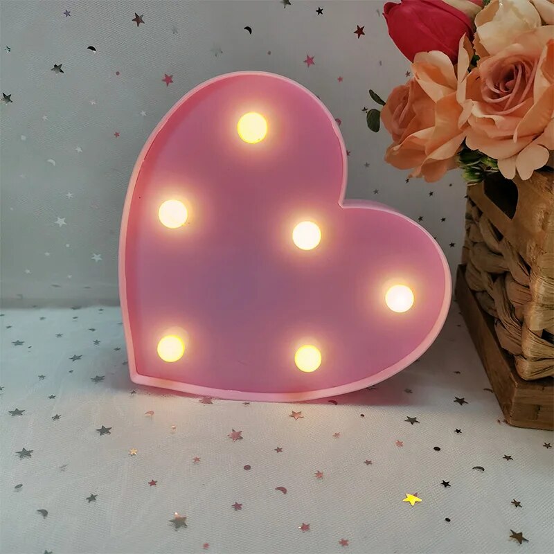 One pink nightlamp heart illuminated by yellow LED's on a white tablecloth with silver and red heart glitter