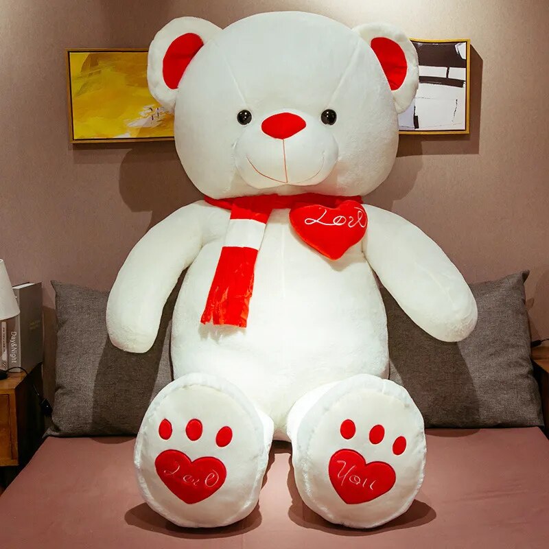 Large white teddy bear wearing red scarf with red ears, nose and bottom paw prints