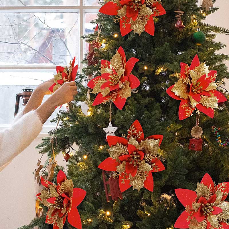 Six fourteen cm red artificial Christmas flowers with a light bronze center on a Christmas tree in an indoor living space.