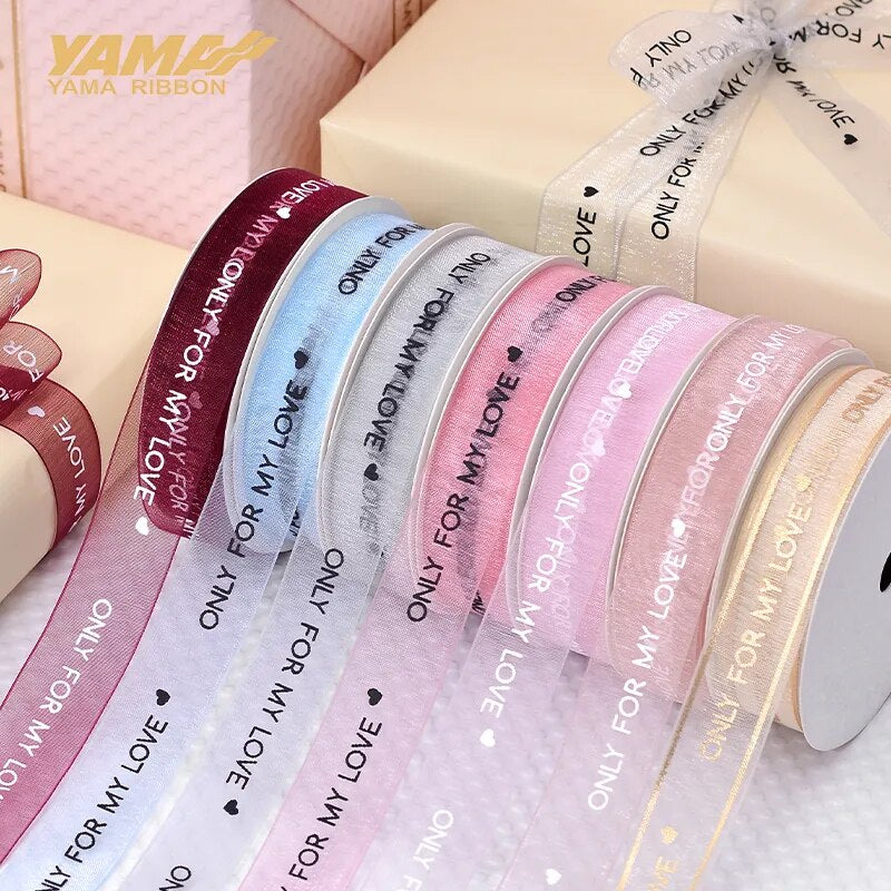 Multiple colors of ribbon that reads only for my love on a wooden table