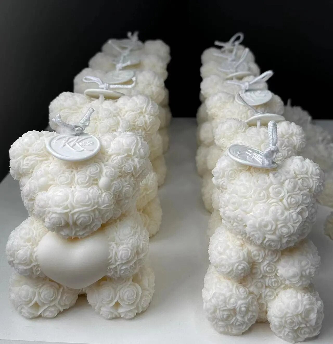 Rows of white chocolate molded bears on white table with black background