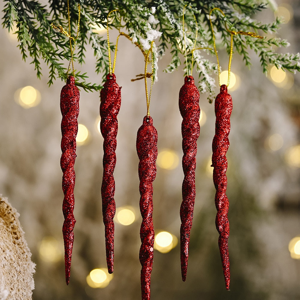 Close up of 5 red icicle ornaments with 11 yellow Christmas tree lights on green Christmas tree.