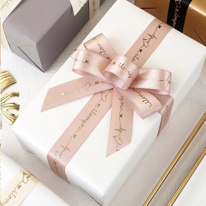 Whiye gift with pink ribbon that reads I love you on a white table