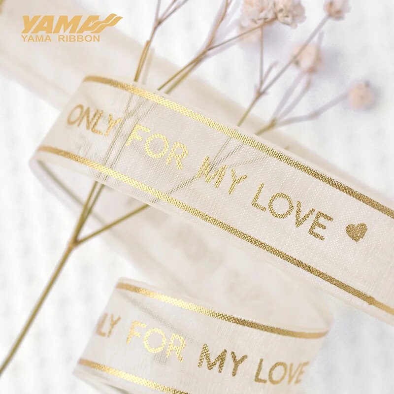 Light gold ribbon that reads only for my love on a grey background