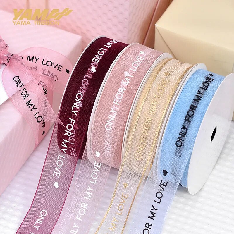 Multiple colors of ribbon that reads only for my love on a white background