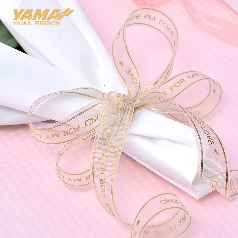 White dinner napkin tied with a light pink ribbon that reads only for my love on a light pink tablecloth