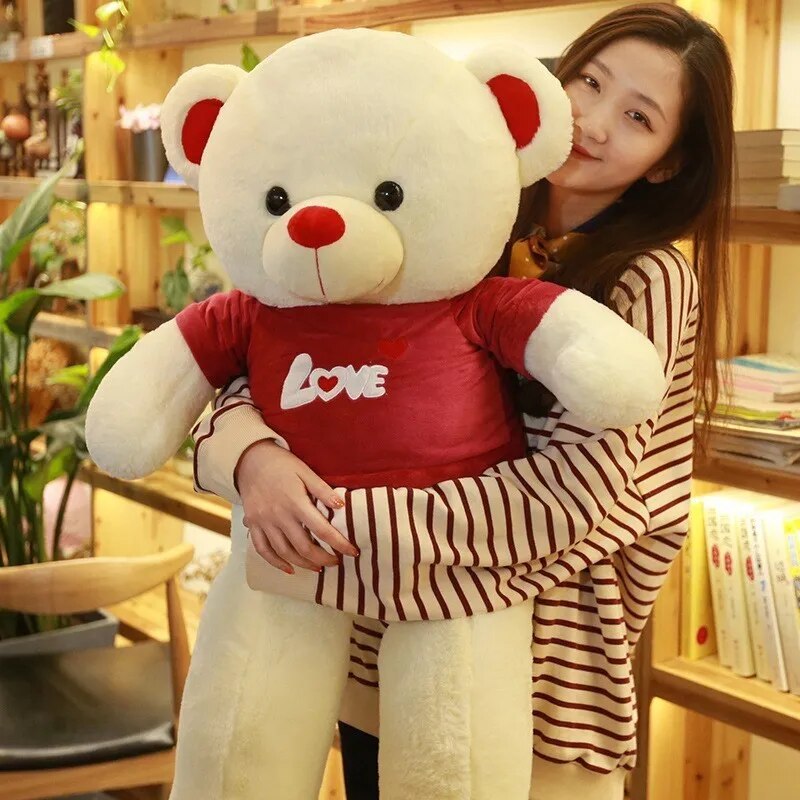 Light beige/ light yellow teddy bear wearing a red t-shirt reading Love written in white lettering